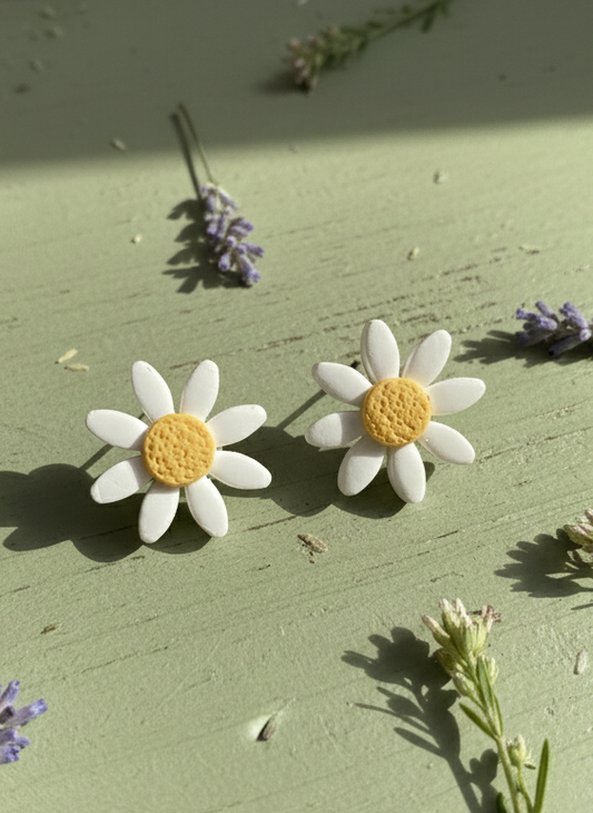 daisy earrings with yellow centers on a green surface