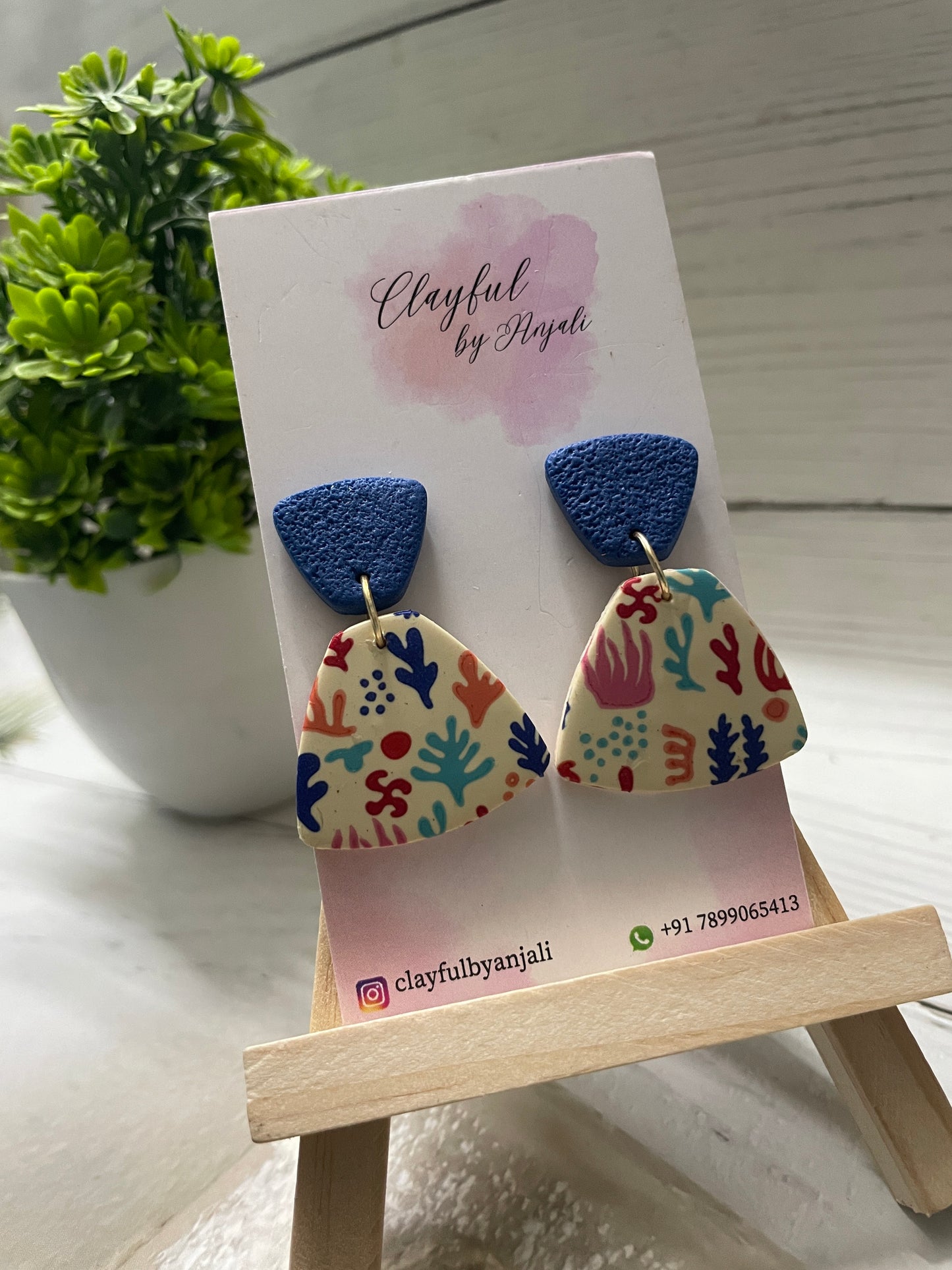 Handcrafted polymer clay earrings from the Transfer Sheet Collection featuring a colorful coastal abstract pattern on a cream fan-shaped base with textured deep blue tops