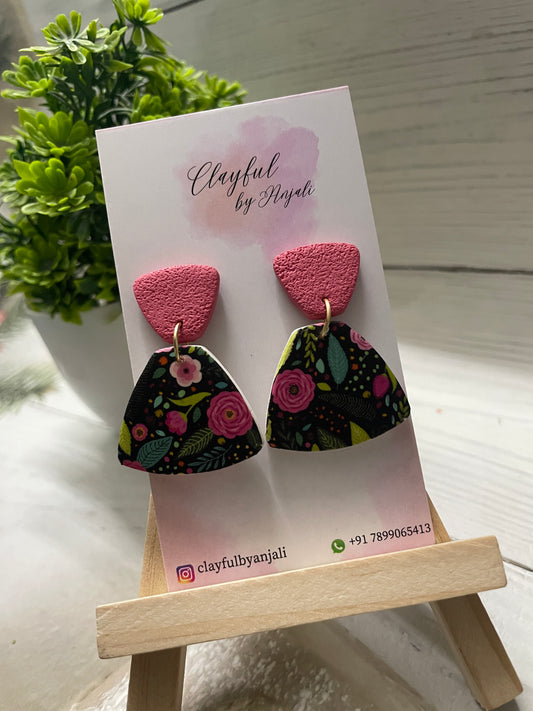 Handcrafted polymer clay earrings named Midnight Meadow Imprint, featuring a colorful floral transfer sheet pattern on a black fan-shaped base with textured rose-pink tops