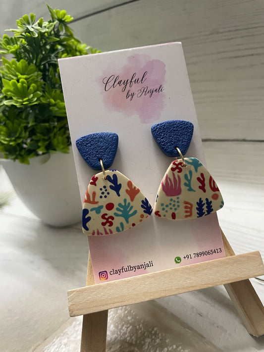 Handcrafted polymer clay earrings from the Transfer Sheet Collection featuring a colorful coastal abstract pattern on a cream fan-shaped base with textured deep blue tops